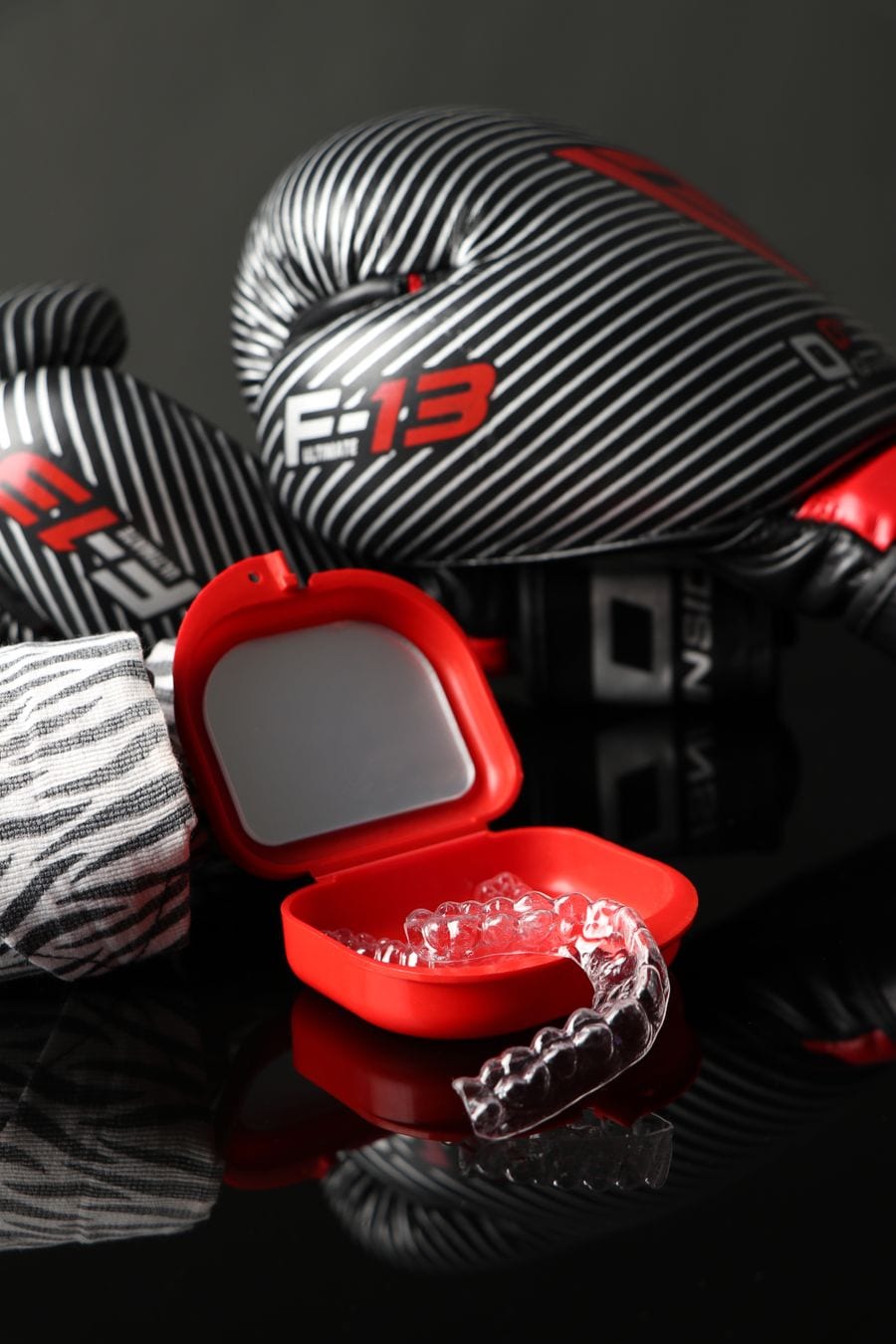 Boxing gloves beside a red case holding a clear mouthpiece